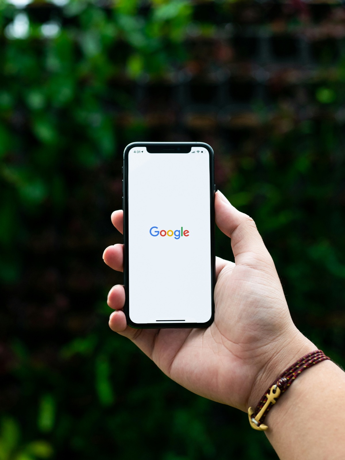 A hand holding a black Android smartphone with its screen lit up against a blurred background