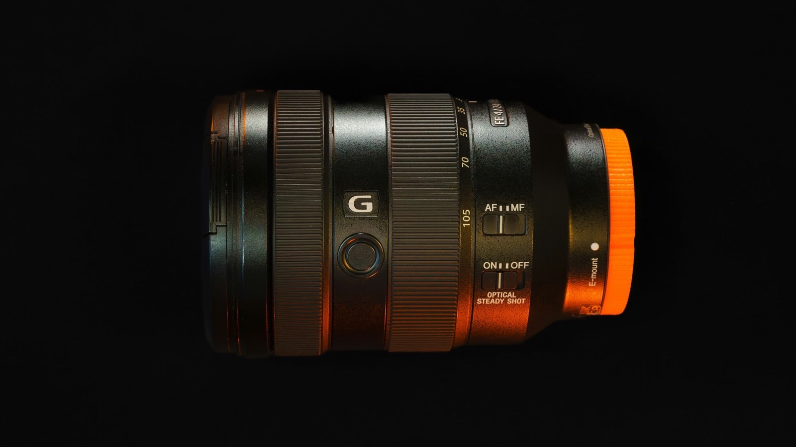 A close-up of a camera zoom lens on a black background, its focal-length markings visible