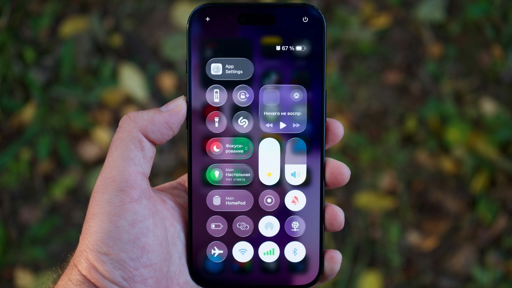 A hand holding an iPhone showing Control Center open, with Focus mode, brightness, and screen recording controls visible