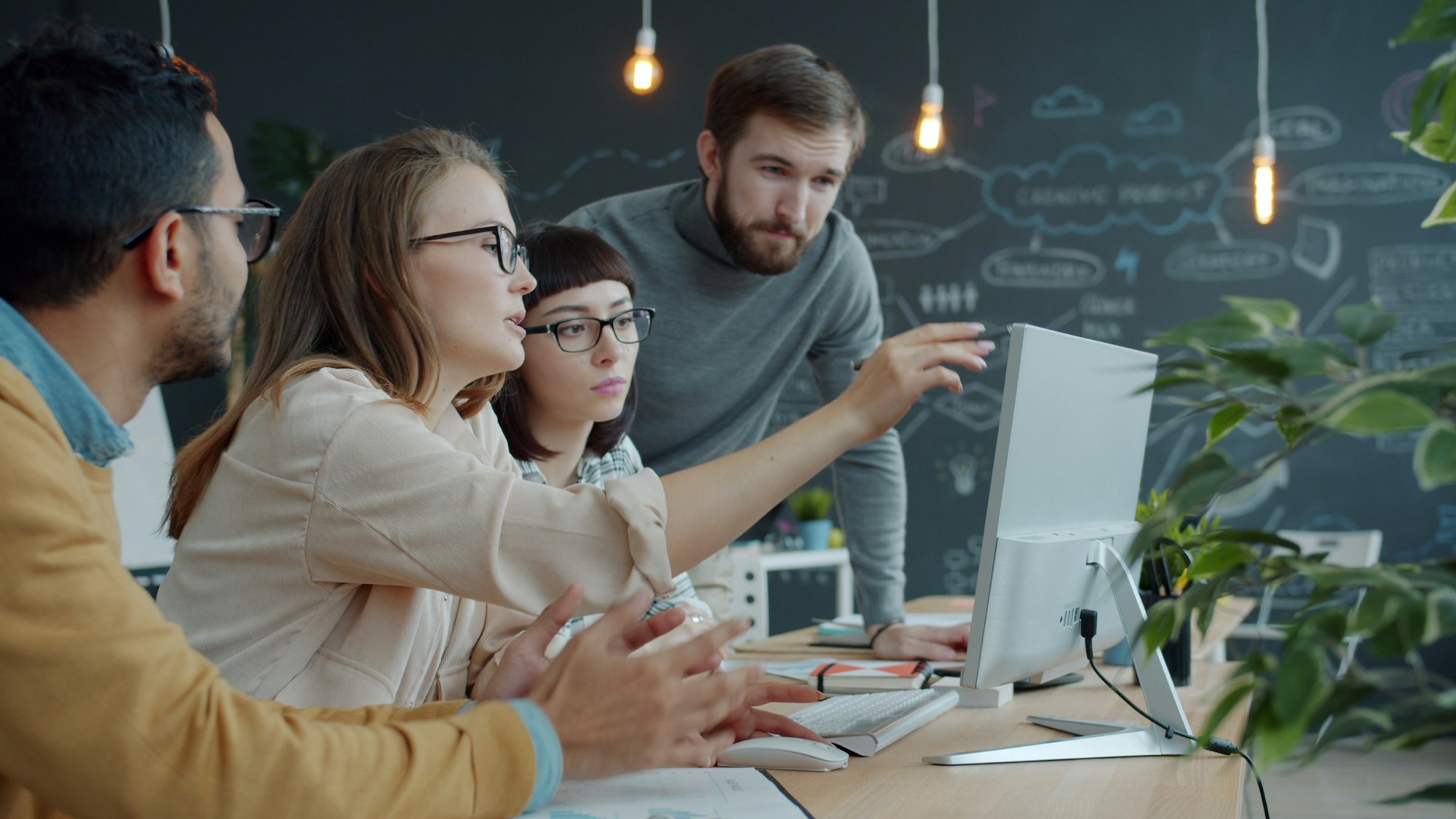 A small team gathered around a laptop in an office, looking at the screen together